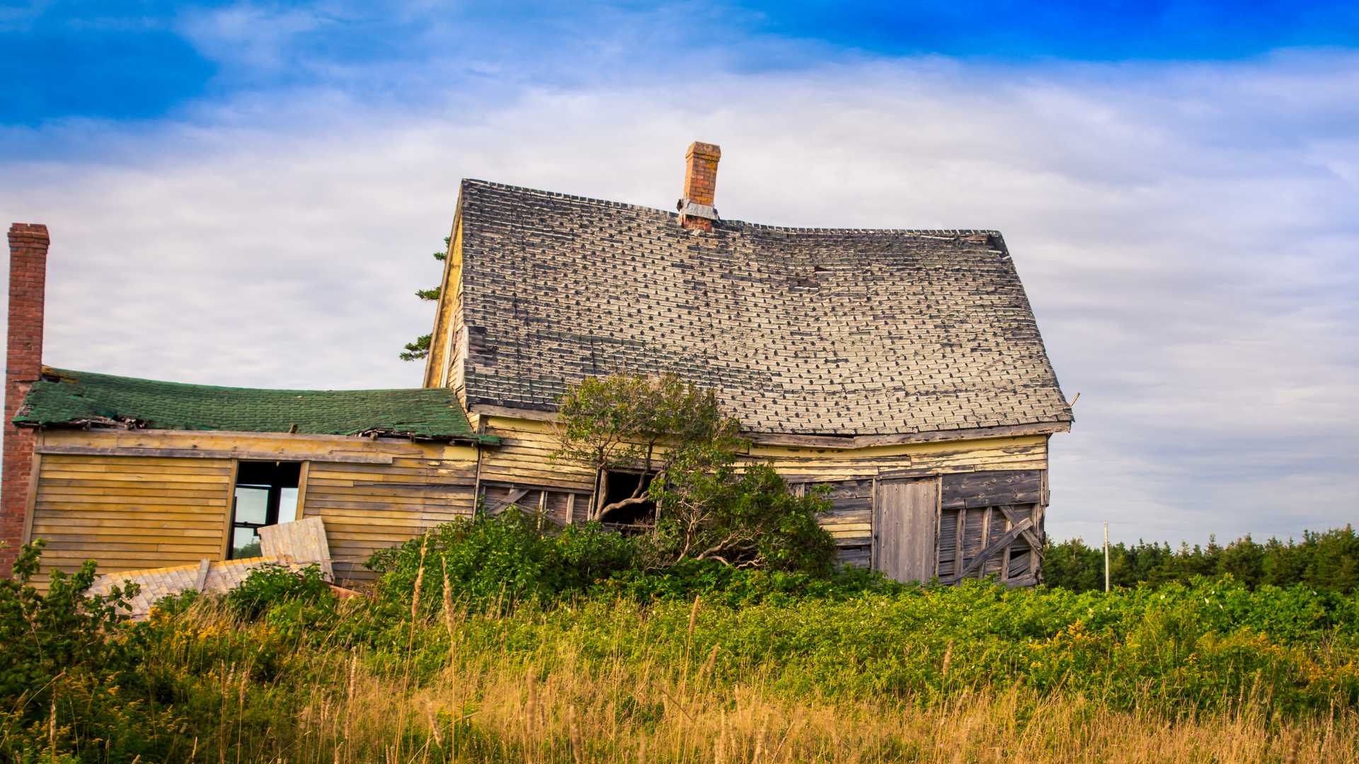 Dilapidated farmhouse that is sagging everywhere and miraculously still standing