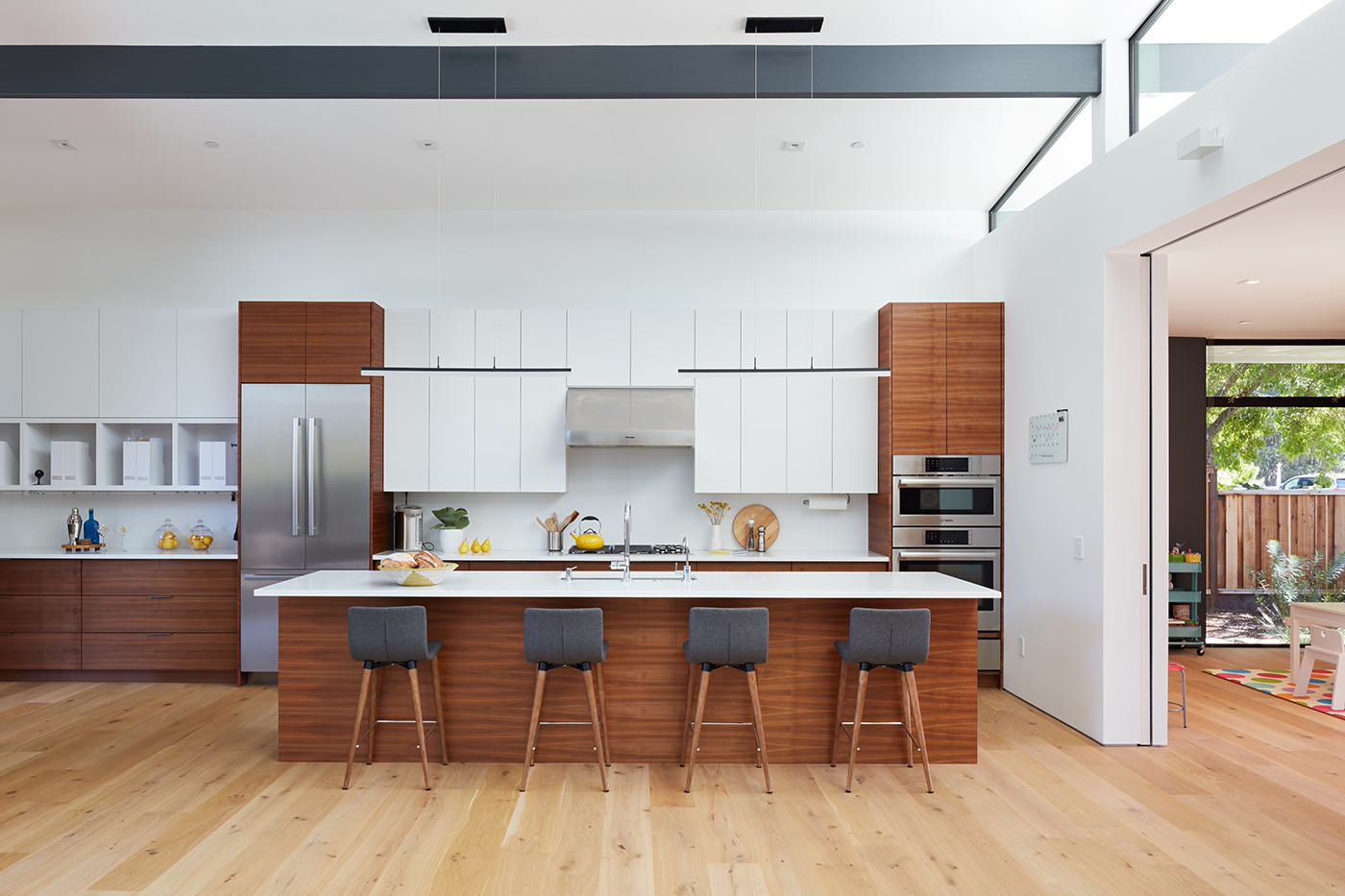 huge kitchen island with single large sink in the middle, directly across from a symmetrical cooktop in the wall cabinetry.