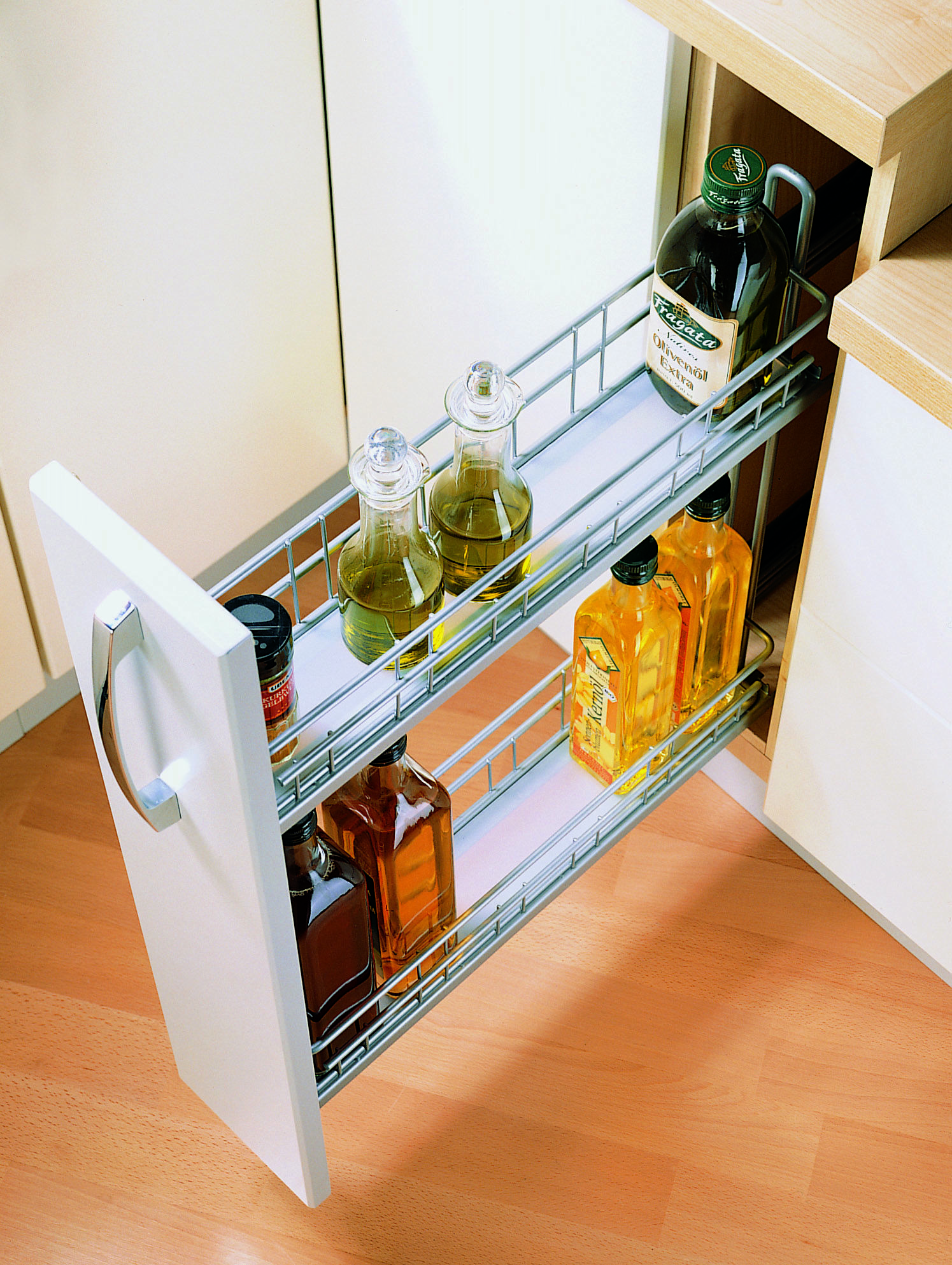 Narrow pull-out drawer with 2 shelves holding glass bottles and a few spices.