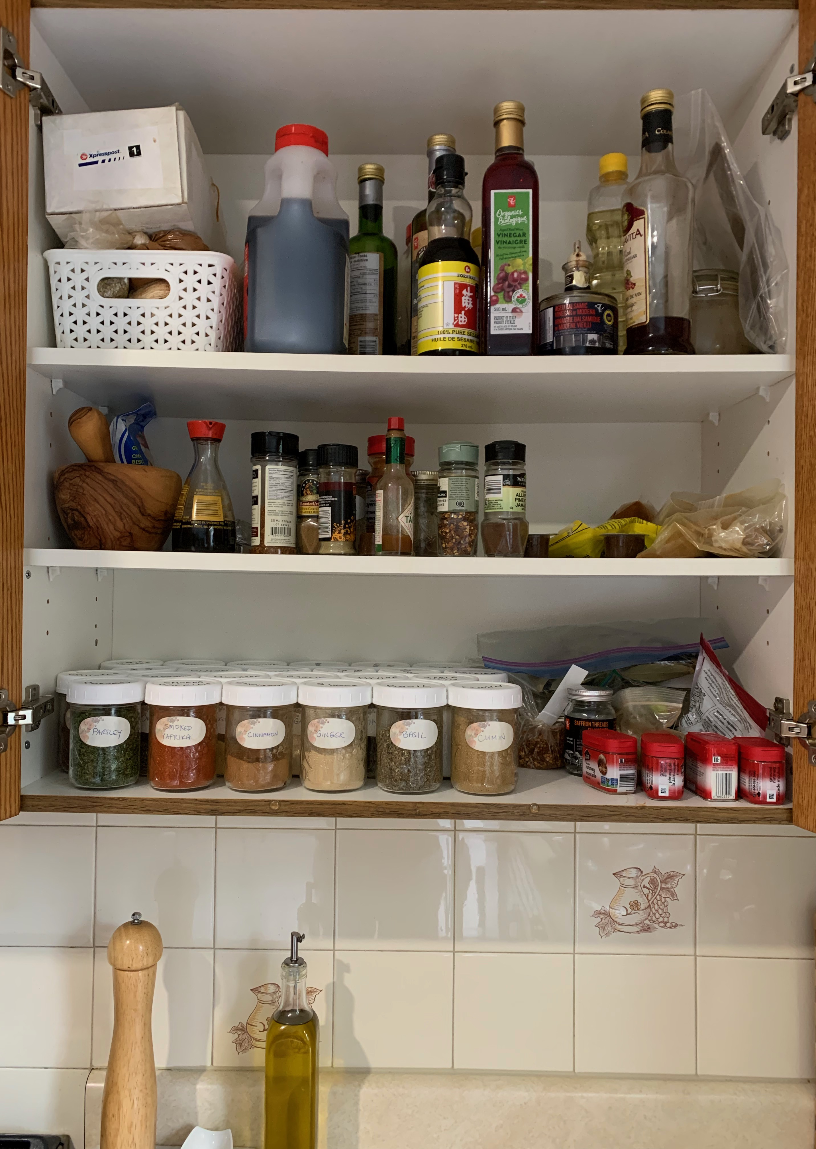 Our spice cabinet with the doors open, showing our collection of spices in mason jars and other cooking oils and sauces.